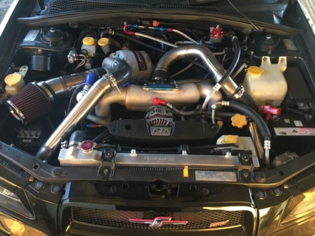 Subaru STI engine bay with top mount turbo, intercooler piping, braided lines and an oil cooler