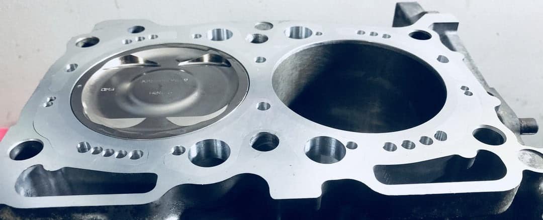 Close-up of a CNC close decked Subaru EJ case half with a forged piston in the bore