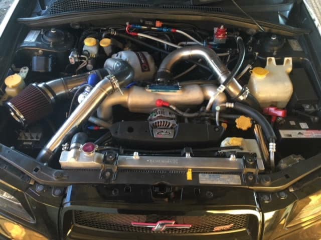 Subaru STI engine bay with a top mount turbo setup, intercooler piping, oil cooler and braided lines fitted at SPR Performance