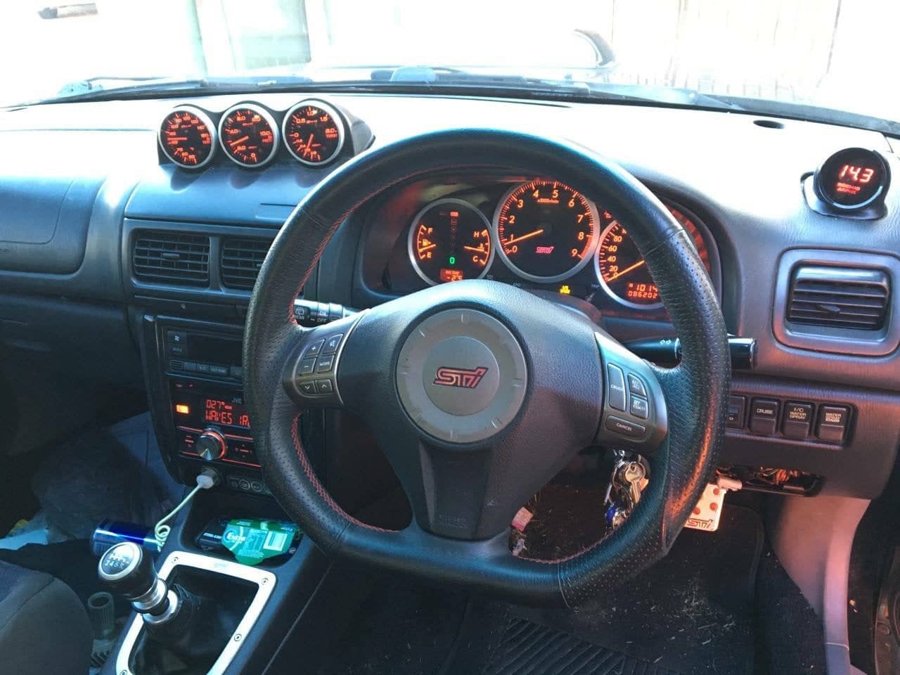 Subaru STI interior with an STI instrument cluster and a three-gauge pod showing boost, oil pressure and oil temperature