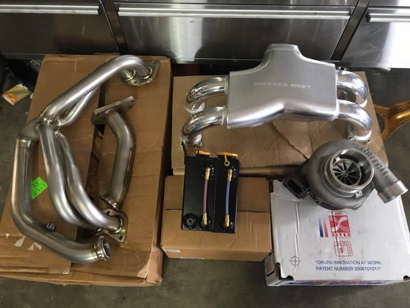 Garrett turbo, tubular manifold, Process West top mount intercooler and fuel rails laid out on a workbench